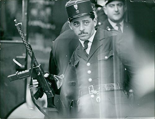 Vintage fotografija policajca koji drži pištolj i skreće pogled.